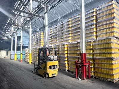 A forklift parked beside stacked pallets of yellow containers
